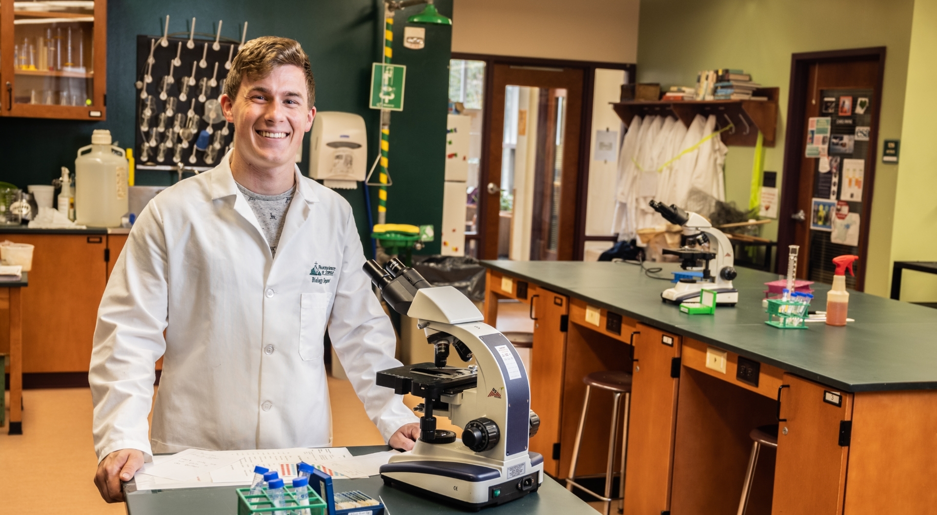 student smiling while working with microscope